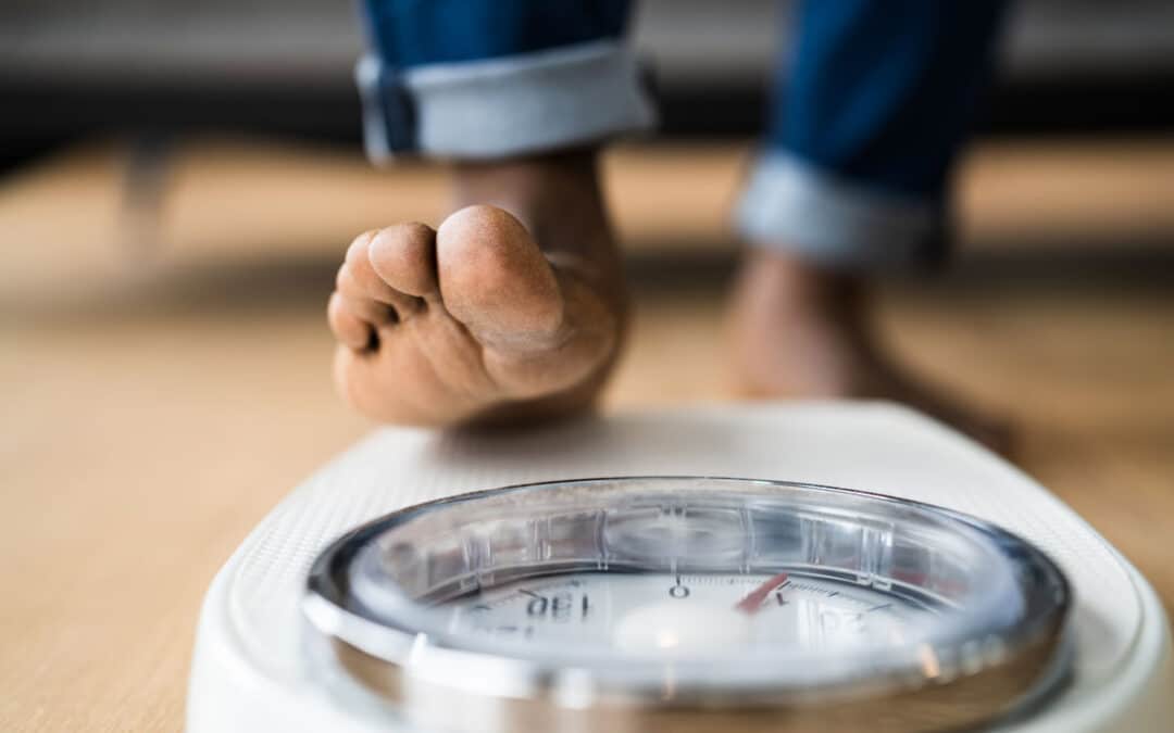 Weight loss myths - man stepping onto scale